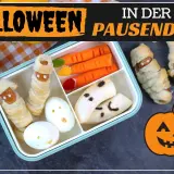 Gruselige Snacks für Halloween: Mumien-Würstchen, Geister-Bananen und Kürbis-Deko in der Pausendose.
