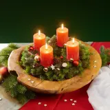 Ein selbstgemachter Adventskranz auf einem Holzteller mit vier brennenden Kerzen, Tannenzweigen, Kugeln und Sternen.
