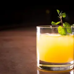 Ein erfrischender Galliano Cocktail mit Eis und Minze auf einem Holztresen.