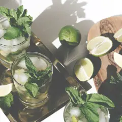 Erfrischender Mohito drink mit Limetten und Minze, serviert auf einem Tablett.
