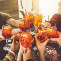 Freunde stoßen mit Aperol Spritz an. Eine bunte longdrinks liste für einen schönen Abend.