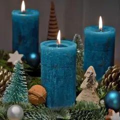 Ein selbstgebastelter Adventskranz mit vier blauen Kerzen, Tannenzweigen, Zapfen und kleinen Bäumchen.