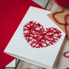 Eine selbstgemachte Valentinstagskarte mit einem roten Herz aus Garn. Perfekt zum Valentinstagskarte basteln.