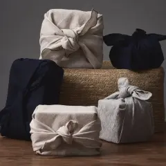 Fünf Geschenke, in Stoff gewickelt und mit Stoffschleifen verziert, warten darauf, ausgepackt zu werden. Eine stilvolle Art, Kleidung zu verpacken, als Geschenk.