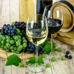 Zwei Gläser Wein, Trauben und ein Holzfass – perfekt für das Kochen mit Alkohol.