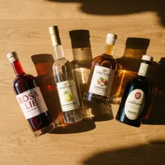 Vier Flaschen mit Spirituosen, darunter ein roter Aperitif, Birnenbrand und Haselnusslikör. Ein polnischer Schnaps könnte hier gut passen.