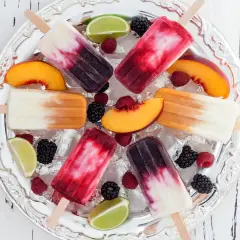 Fruchtige Eis am Stiel mit Beeren, Pfirsich und Limette auf Eis. Ein erfrischender Genuss, der an eis mit Alkohol erinnert.