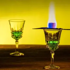 Grüner Absinth brennt über einem Zuckerwürfel in einem Glas. Die Zubereitung lässt die Absinth-Wirkung erahnen.