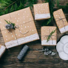 Geschenkpapier bemalen für einen Geburtstag: Geschenke mit weißen Punkten und Tannenzweigen, bereit zum Verschenken.