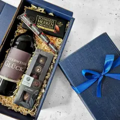 Ein edler Geschenkkorb zum 50. Geburtstag für einen Mann: Rotwein, dunkle Schokolade und Pralinen.