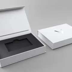 Elegante weiße Geschenkbox mit schwarzem Inlay, ideal für Karten verpacken Ideen. Ein silbernes Logo ziert den Deckel.