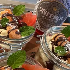 Italienischer Schnaps nach dem Essen: Leckere Desserts im Glas mit Schokolade, Früchten und Minze, daneben eine Flasche Osterol Likör.