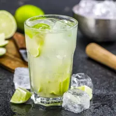 Erfrischende Caipirinha-Varianten mit frischen Limetten, Eis und einem Mörser.