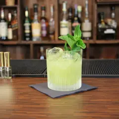 Ein erfrischender grüner Cocktail mit Minze, Eis und einer Flasche Bitters. Perfekt, um zu sehen, mit was man Tequila mischt.