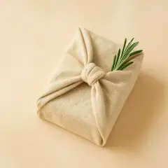 Ein Geschenk, in Stoff gewickelt und mit einem Rosmarinzweig verziert. Tolle geschenke verpacken ideen für einen natürlichen Look.