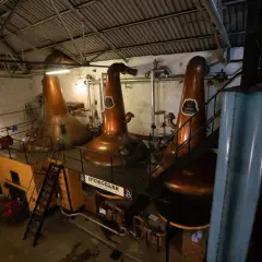 Drei große Kupfer-Brennblasen (pot still) in einer Brennerei, bereit zur Destillation.