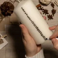 Hände beschriften eine Kerze mit Zahlen für einen Adventskalender. So lassen sich Adventskalender Geschenke selber machen.