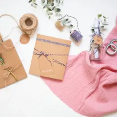 Kreatives **Gutschein verpacken** mit **Geschenkpapier** und Naturmaterialien. Eine Flasche mit Botschaft und ein kleines Päckchen warten auf ihre Übergabe.