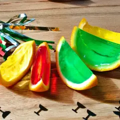 Farbige Jelly Shots in Orangenschalen, dekoriert mit Party-Konfetti. Ein süßer Genuss für jede Feier!