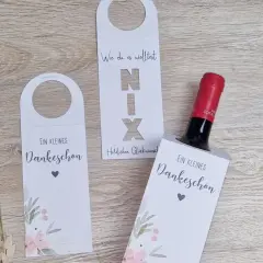Eine Weinflasche mit Geld verpacken: weiße Hüllen mit floralem Muster und Schriftzug "Ein kleines Dankeschön".