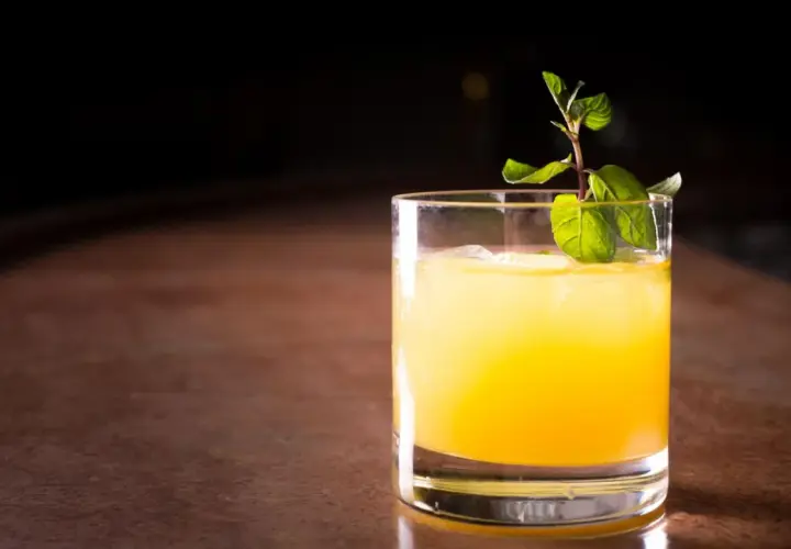 Ein erfrischender Galliano Cocktail mit Eis und Minze auf einem Holztresen.