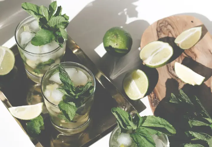Erfrischender Mohito drink mit Limetten und Minze, serviert auf einem Tablett.