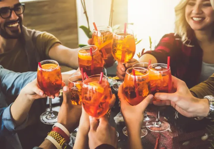 Freunde stoßen mit Aperol Spritz an. Eine bunte longdrinks liste für einen schönen Abend.