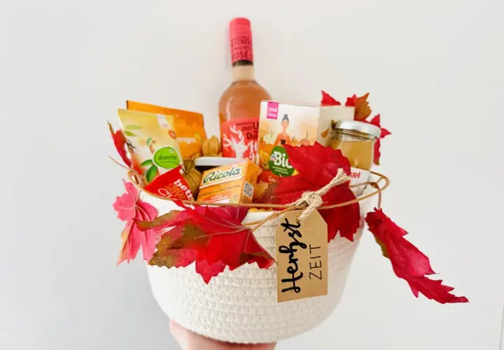 Ein liebevoll gefüllter Geschenkkorb zum Geburtstag, dekoriert mit Herbstlaub. Enthält Wein, Snacks und Honig.