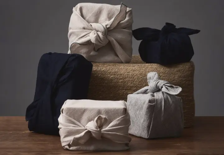 Fünf Geschenke, in Stoff gewickelt und mit Stoffschleifen verziert, warten darauf, ausgepackt zu werden. Eine stilvolle Art, Kleidung zu verpacken, als Geschenk.