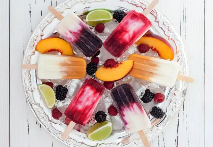 Fruchtige Eis am Stiel mit Beeren, Pfirsich und Limette auf Eis. Ein erfrischender Genuss, der an eis mit Alkohol erinnert.