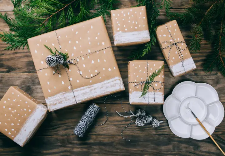 Geschenkpapier bemalen für einen Geburtstag: Geschenke mit weißen Punkten und Tannenzweigen, bereit zum Verschenken.