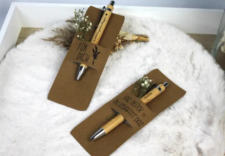 Zwei liebevoll verpackte Stifte als Geschenk. Einer mit "Für dich" und der andere mit "Viel Glück du schaffst das" beschriftet, beide mit kleinen Blumen verziert.