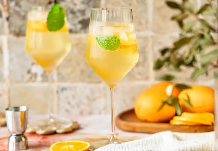 Erfrischender Lillet Spritz mit Eis, Minze und Orangenscheiben. Perfekt für einen sonnigen Nachmittag.