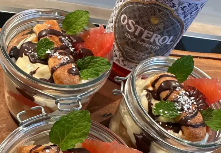 Italienischer Schnaps nach dem Essen: Leckere Desserts im Glas mit Schokolade, Früchten und Minze, daneben eine Flasche Osterol Likör.