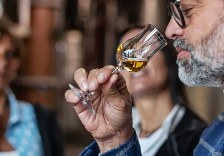 Mann mit Bart schnuppert an einem Grappa-Glas. So trinkt man Grappa: erst riechen, dann genießen.