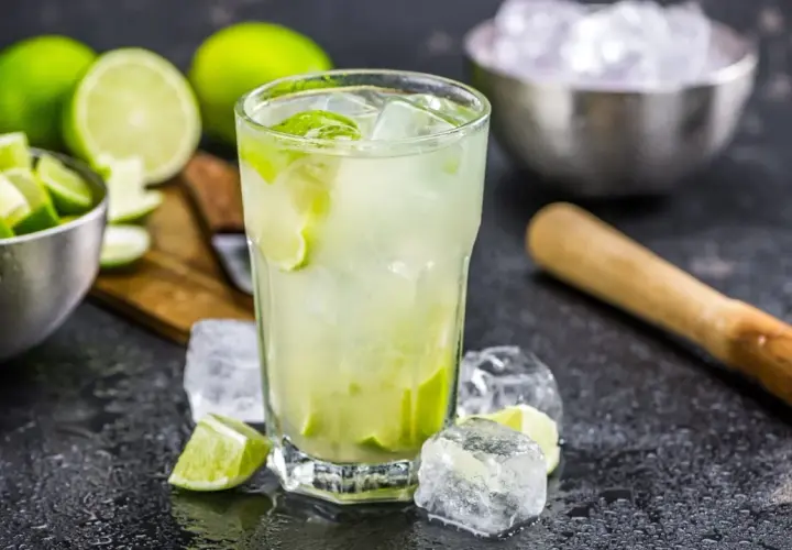 Erfrischende Caipirinha-Varianten mit frischen Limetten, Eis und einem Mörser.