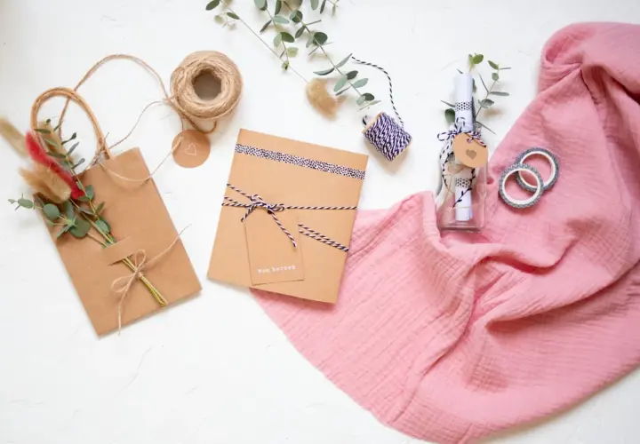 Kreatives **Gutschein verpacken** mit **Geschenkpapier** und Naturmaterialien. Eine Flasche mit Botschaft und ein kleines Päckchen warten auf ihre Übergabe.