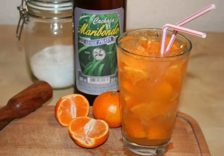 Ein Glas mit Eis und Orangenscheiben, daneben eine Flasche "Cachaça Maribondo". So wird Cachaça, ein brasilianischer Zuckerrohrschnaps, oft serviert.