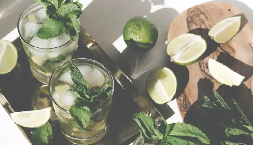 Erfrischender Mohito drink mit Limetten und Minze, serviert auf einem Tablett.