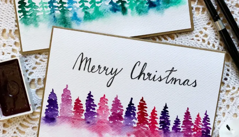 Zwei handgemalte Weihnachtskarten mit Aquarell-Tannenbäumen in Lila- und Grüntönen. Perfekt zum Thema Weihnachtskarten selber malen.