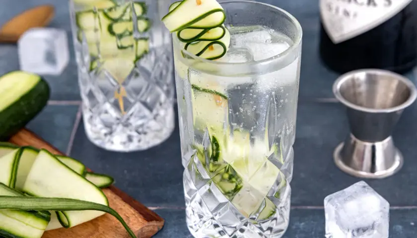 Erfrischender Gin mit Gurke, Eiswürfeln und einer dekorativen Gurkenspirale. Perfekt für einen warmen Sommertag.