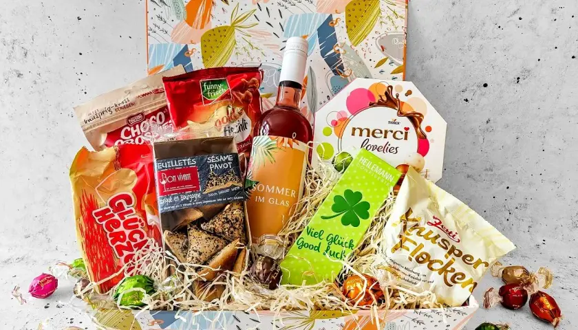 Ein liebevoll zusammengestellter Geschenkkorb zum 70. Geburtstag einer Frau, gefüllt mit Schokolade, Keksen, Wein und Glücksbringern.