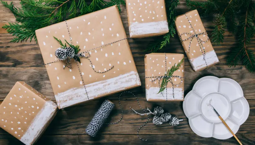 Geschenkpapier bemalen für einen Geburtstag: Geschenke mit weißen Punkten und Tannenzweigen, bereit zum Verschenken.