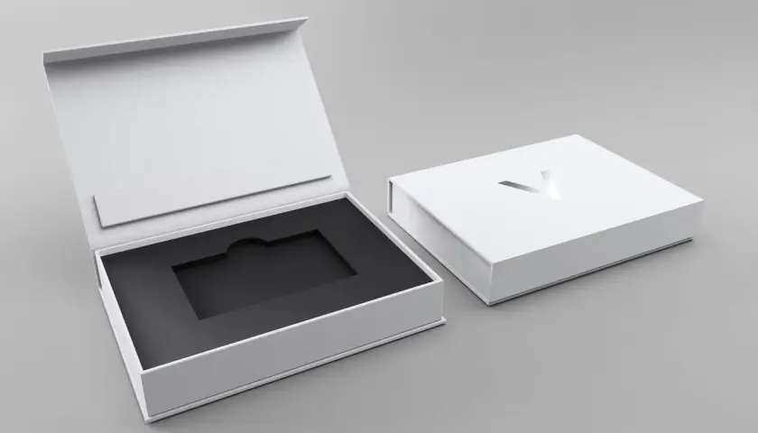 Elegante weiße Geschenkbox mit schwarzem Inlay, ideal für Karten verpacken Ideen. Ein silbernes Logo ziert den Deckel.