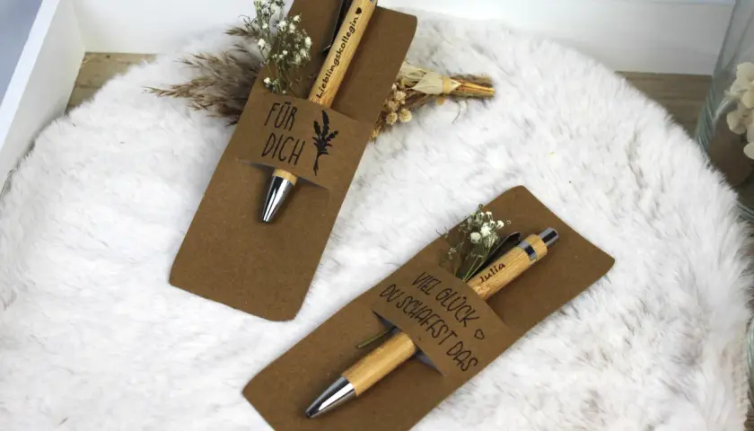 Zwei liebevoll verpackte Stifte als Geschenk. Einer mit "Für dich" und der andere mit "Viel Glück du schaffst das" beschriftet, beide mit kleinen Blumen verziert.