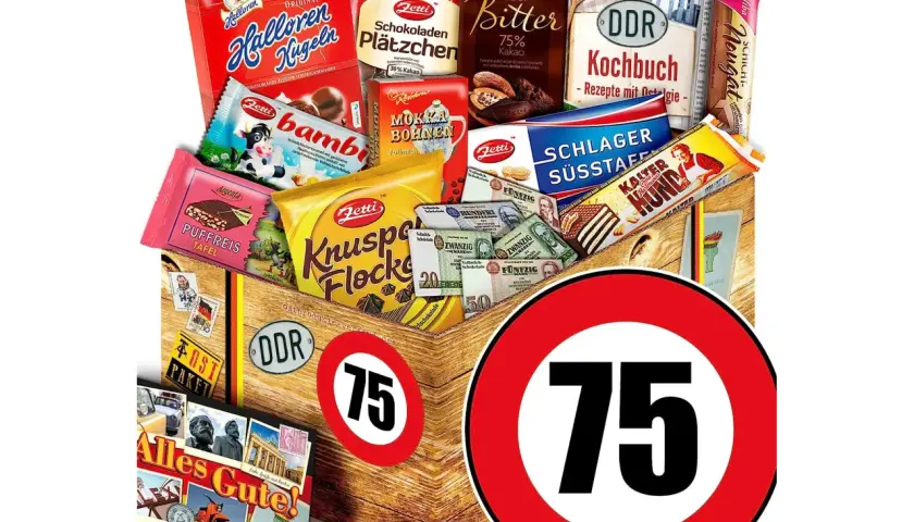 Ein liebevoll zusammengestelltes Geschenkpaket zum 75. Geburtstag eines Mannes, gefüllt mit Ostalgie-Süßigkeiten, DDR-Kochbuch und Erinnerungsstücken.