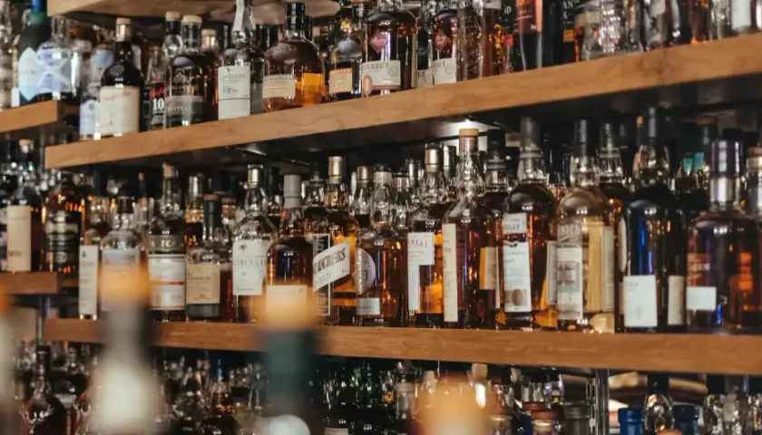 Regale voller Flaschen mit bernsteinfarbenem Whisky oder Whiskey. Eine große Auswahl für Kenner.