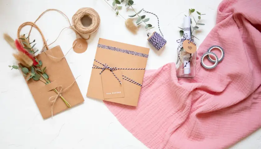 Kreatives **Gutschein verpacken** mit **Geschenkpapier** und Naturmaterialien. Eine Flasche mit Botschaft und ein kleines Päckchen warten auf ihre Übergabe.