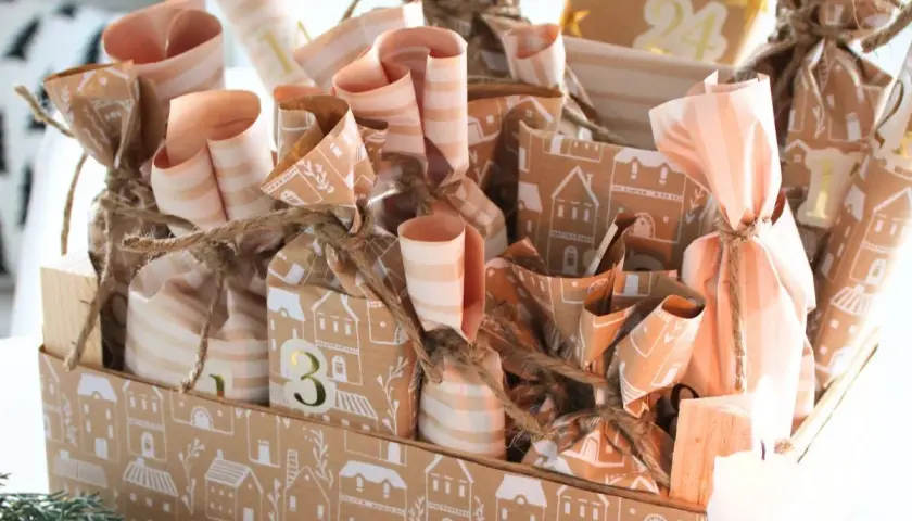 Ein liebevoll gestalteter Adventskalender mit vielen kleinen Päckchen, die mit Häusern und Streifen verziert sind. Tolle Adventskalender Gutscheine Ideen für jeden Tag.