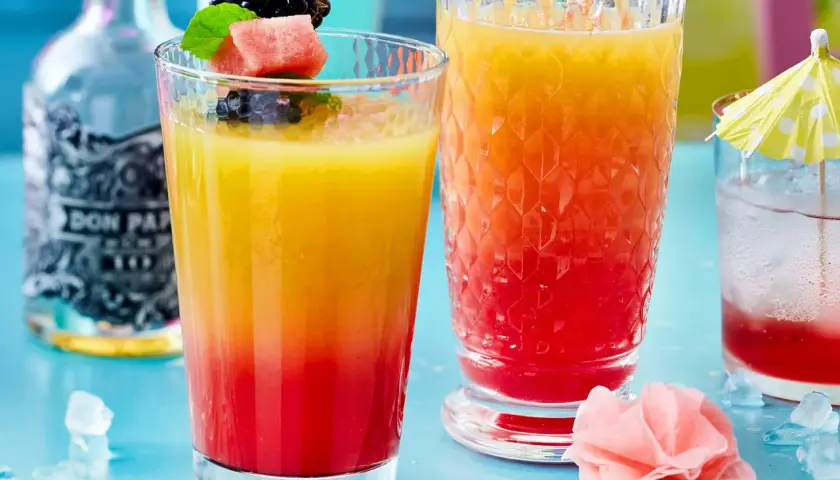 Zwei bunte Rum-Cocktails mit Früchten und Eis. Perfekt für easy Rum Cocktails an einem warmen Tag.